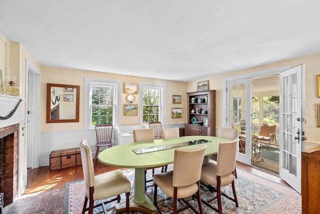 dining area with a brick fireplace, wallpapered walls, and french doors