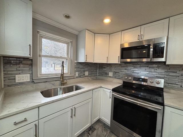 kitchen featuring white cabinets, appliances with stainless steel finishes, ornamental molding, and a sink