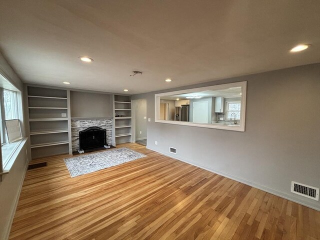 unfurnished living room featuring visible vents, baseboards, and hardwood / wood-style floors