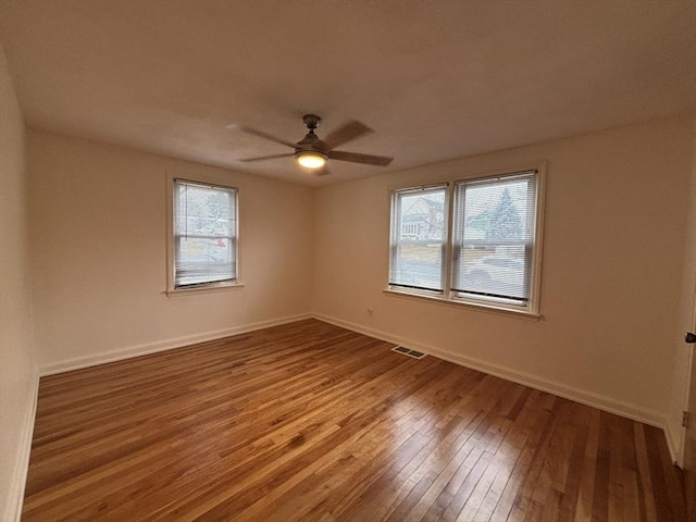 spare room featuring ceiling fan, plenty of natural light, hardwood / wood-style floors, and visible vents