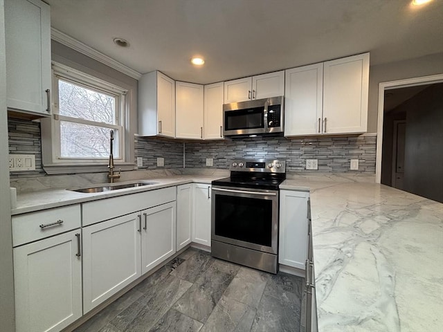 kitchen featuring a sink, crown molding, decorative backsplash, white cabinets, and appliances with stainless steel finishes