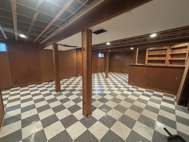 finished basement featuring light floors, visible vents, and wood walls