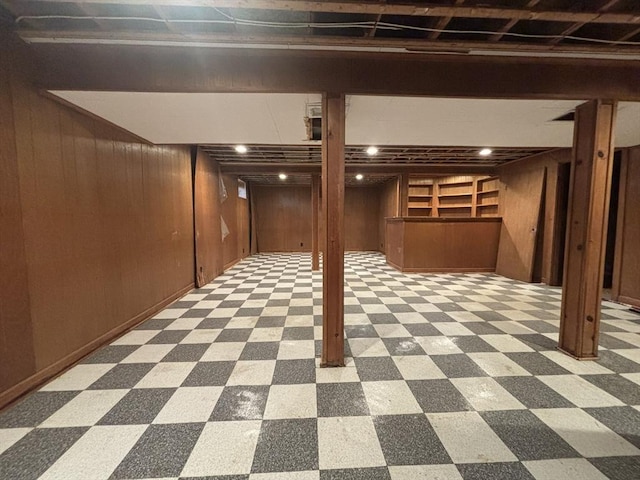 finished basement with wooden walls and tile patterned floors