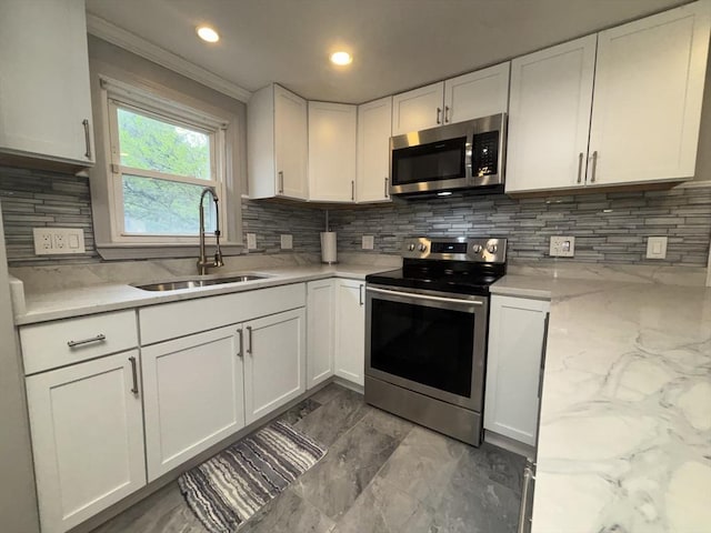 kitchen with a sink, stainless steel appliances, ornamental molding, backsplash, and white cabinets