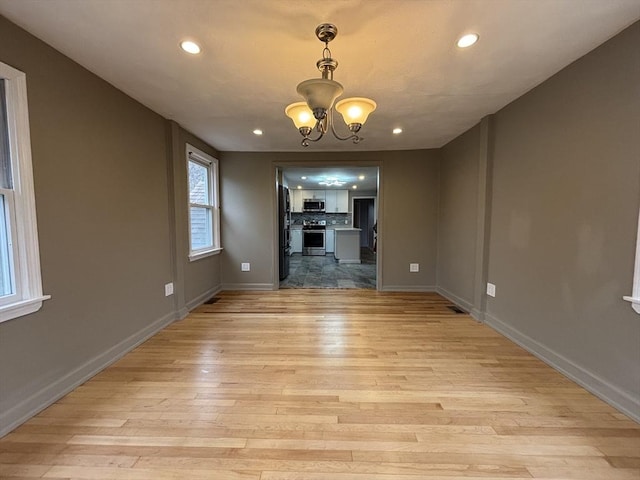 unfurnished dining area with an inviting chandelier, light wood-type flooring, baseboards, and recessed lighting