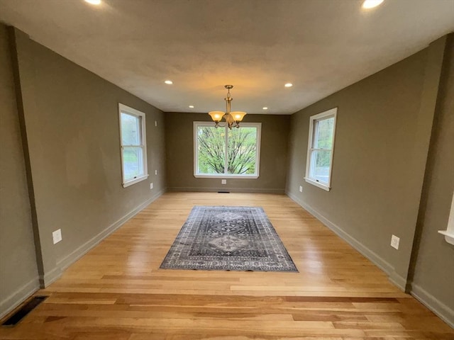 unfurnished dining area featuring a notable chandelier, recessed lighting, baseboards, light wood finished floors, and visible vents