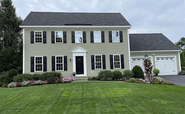 14 Cavite St, Devens, MA 01434 - colonial-style house with an attached garage, a front lawn, driveway, and a shingled roof