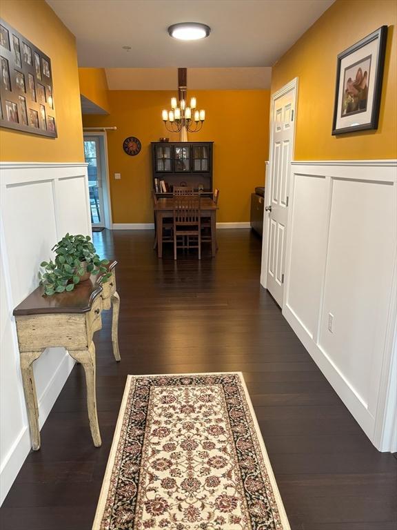 14 Cavite St, Devens, MA 01434 - corridor featuring a chandelier, dark wood-style floors, wainscoting, baseboards, and a decorative wall
