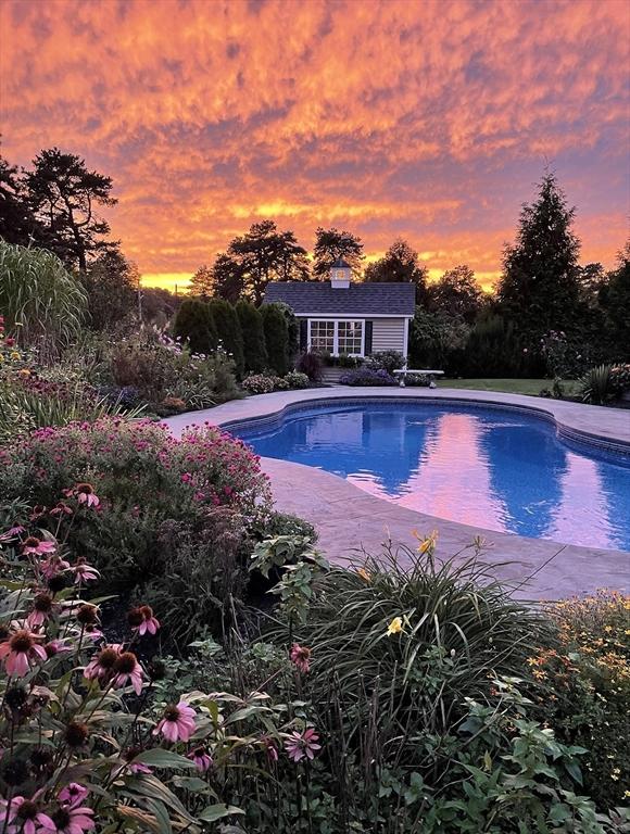 14 Cavite St, Devens, MA 01434 - pool at dusk with an outdoor structure, a storage structure, and an outdoor pool