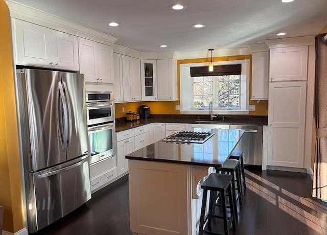 14 Cavite St, Devens, MA 01434 - kitchen featuring appliances with stainless steel finishes, dark wood-type flooring, white cabinets, a sink, and a kitchen bar