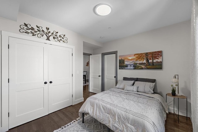 bedroom featuring a closet, dark wood-type flooring, and baseboards