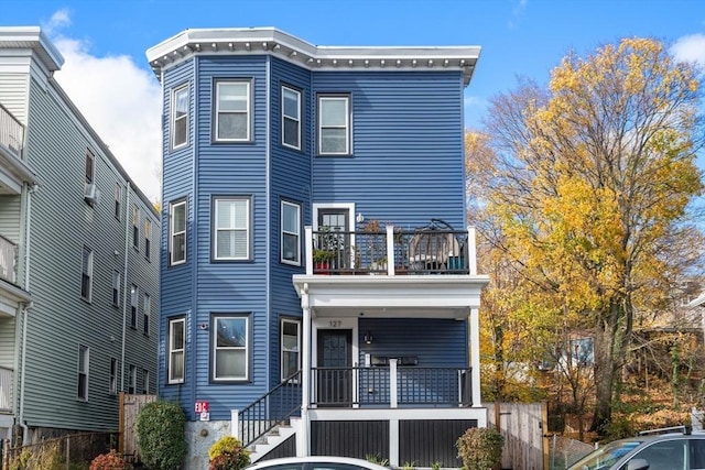 view of front of house featuring a balcony, a porch, and fence