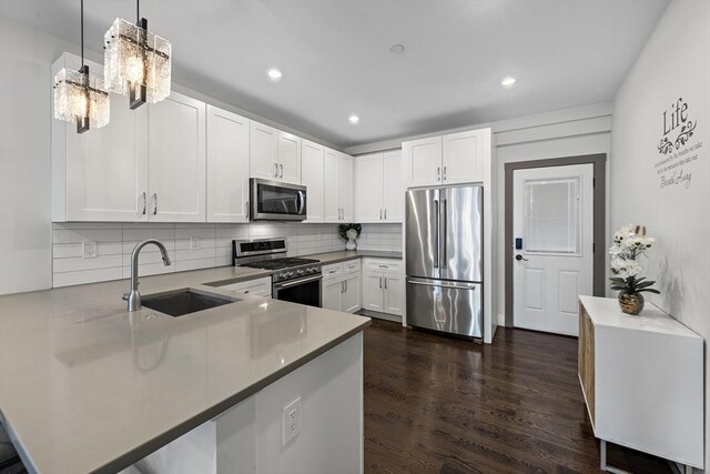 kitchen featuring tasteful backsplash, a peninsula, white cabinets, stainless steel appliances, and a sink