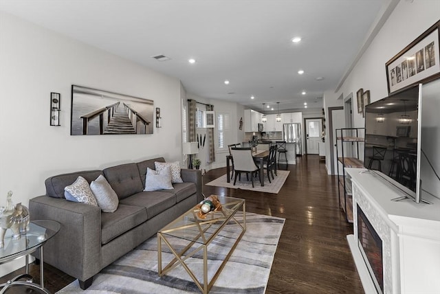 living area with dark wood-type flooring, recessed lighting, and visible vents