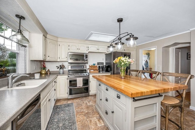 11 Florence Rd, Lowell, MA 01851 - kitchen with stainless steel appliances, a sink, a breakfast bar area, hanging light fixtures, and crown molding