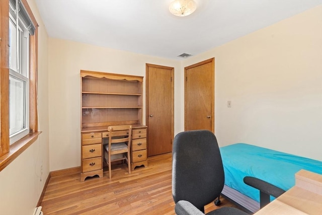 home office with a wealth of natural light, light wood-type flooring, visible vents, and baseboards