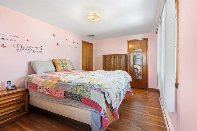 bedroom featuring a baseboard radiator, wood finished floors, and visible vents