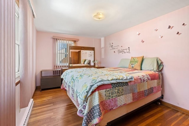 bedroom featuring a baseboard radiator, wood finished floors, and baseboards