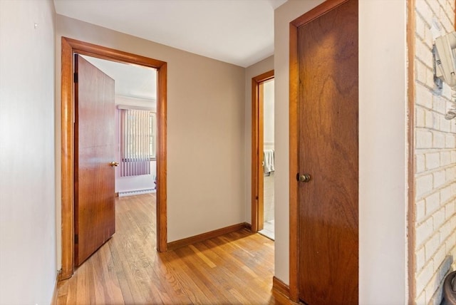 corridor with light wood-style floors and baseboards