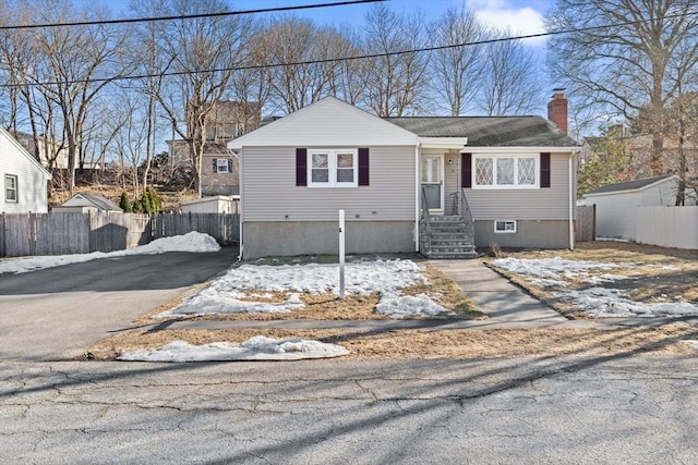 view of front of home with aphalt driveway, fence, and a chimney