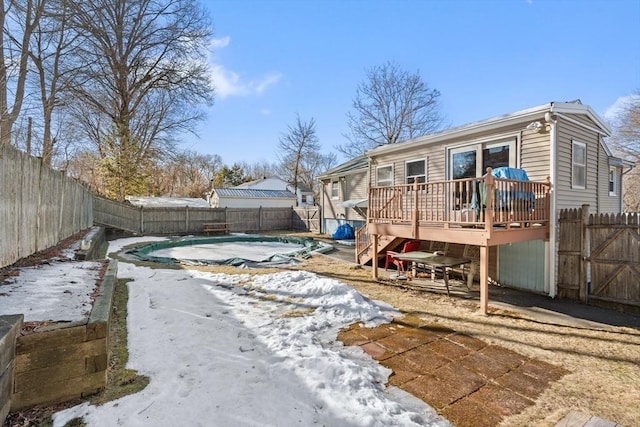 rear view of property with a fenced in pool, a gate, a fenced backyard, and a deck