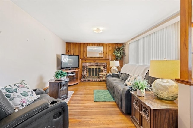 living room featuring light wood finished floors, a brick fireplace, and wooden walls