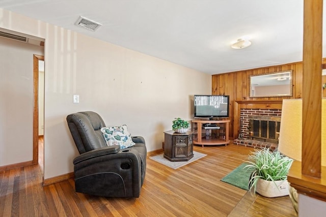 living room with visible vents, a fireplace, baseboards, and wood finished floors