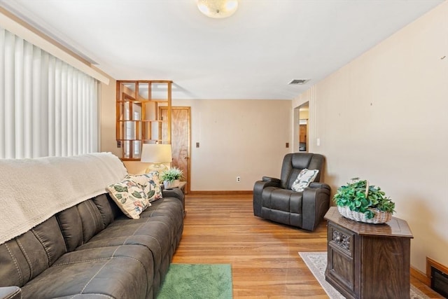 living area featuring visible vents, light wood-style flooring, and baseboards