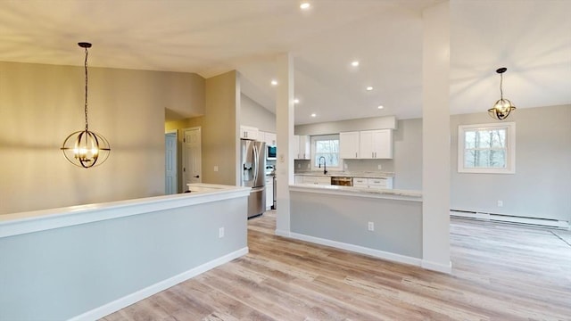 kitchen featuring decorative light fixtures, a baseboard radiator, sink, white cabinets, and stainless steel appliances