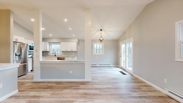 kitchen featuring white cabinetry, decorative light fixtures, vaulted ceiling, baseboard heating, and appliances with stainless steel finishes