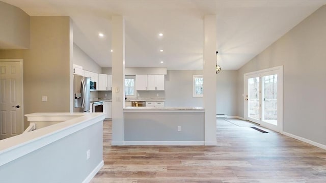 kitchen featuring stainless steel appliances, light hardwood / wood-style floors, vaulted ceiling, and white cabinets