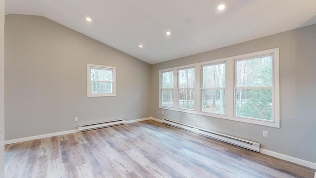 spare room featuring light hardwood / wood-style flooring, a baseboard heating unit, and vaulted ceiling