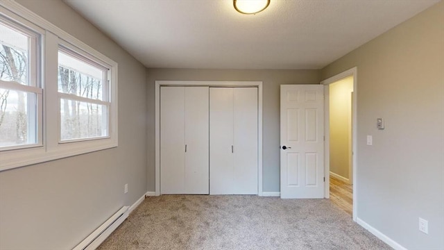 unfurnished bedroom with a baseboard radiator, light colored carpet, and a closet