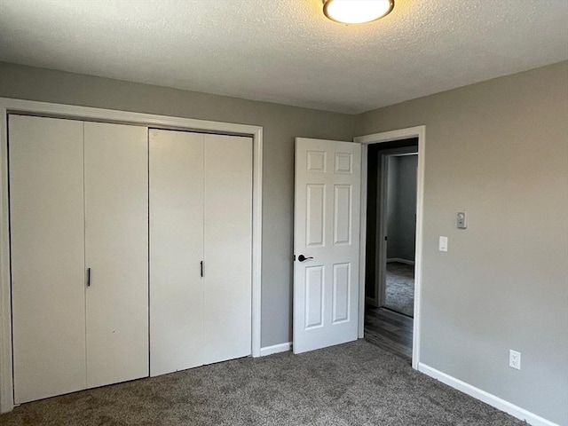 unfurnished bedroom featuring dark carpet, a closet, and a textured ceiling