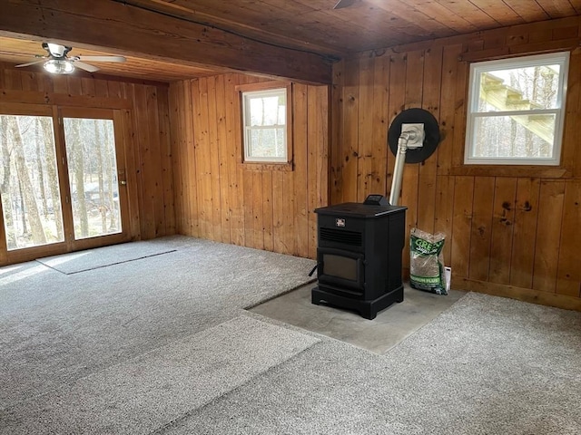 interior space with a wood stove, wooden ceiling, and wooden walls