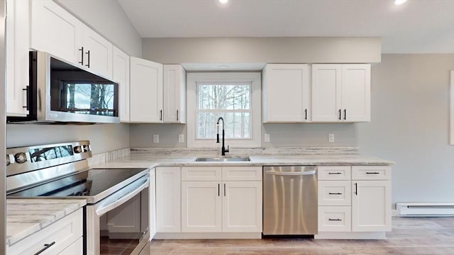 kitchen with a baseboard heating unit, white cabinetry, appliances with stainless steel finishes, and sink