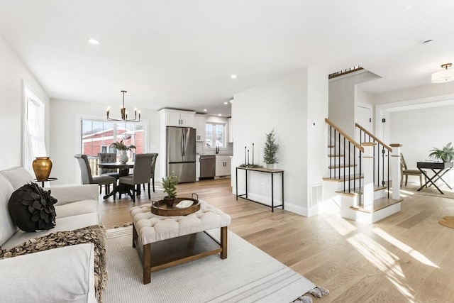 living room with a chandelier, light wood-type flooring, and sink