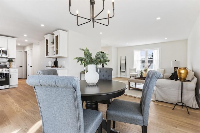 dining room with light hardwood / wood-style floors and an inviting chandelier