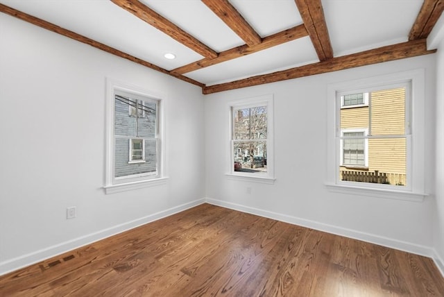 spare room featuring hardwood / wood-style floors and beamed ceiling