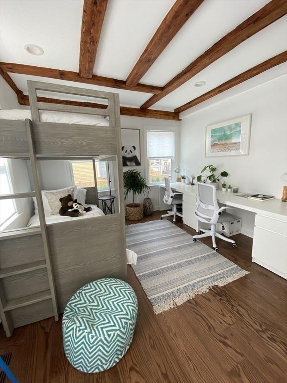 bedroom featuring dark hardwood / wood-style floors, beam ceiling, and built in desk