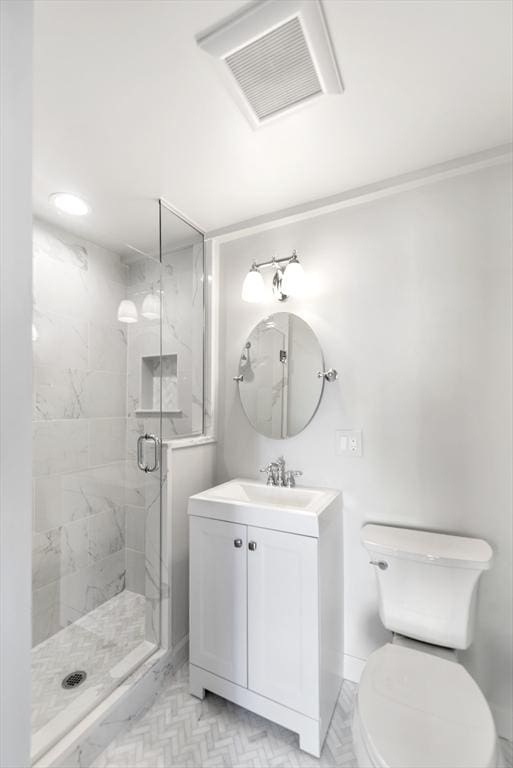 bathroom featuring vanity, toilet, and a shower with shower door