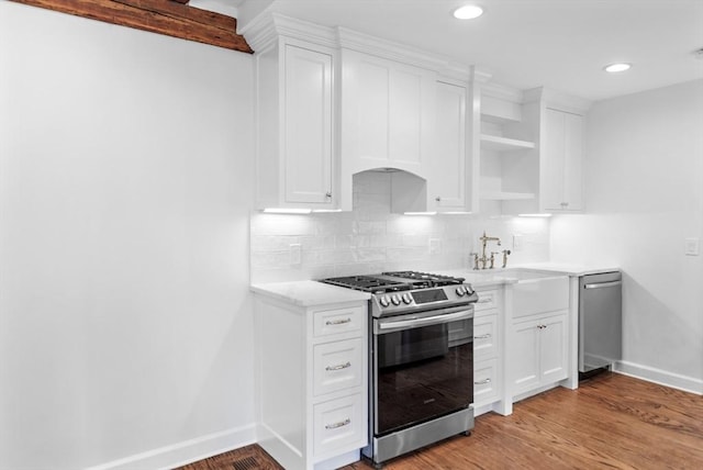 kitchen with sink, light hardwood / wood-style flooring, tasteful backsplash, white cabinetry, and stainless steel appliances