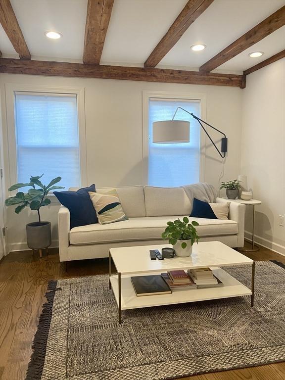 living room featuring dark hardwood / wood-style flooring and beamed ceiling