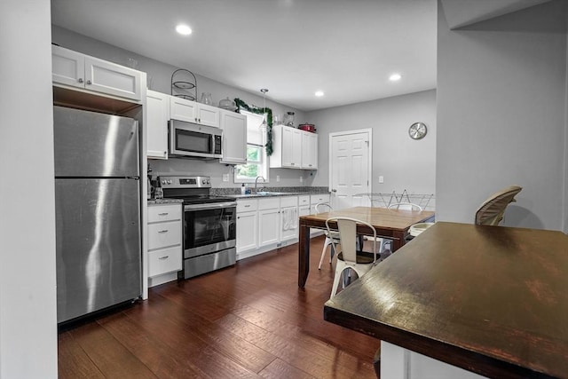 kitchen with dark hardwood / wood-style flooring, sink, white cabinets, and stainless steel appliances