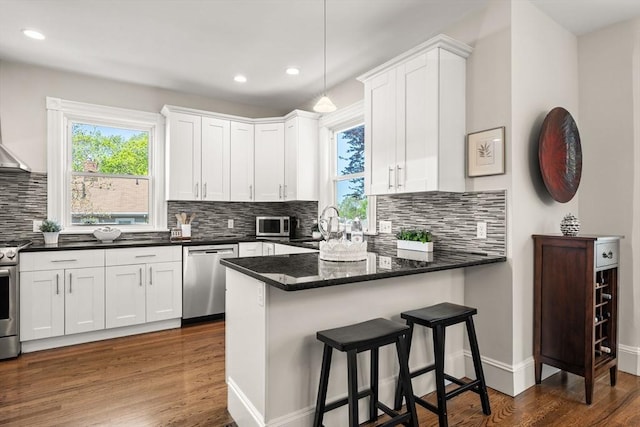 kitchen with appliances with stainless steel finishes, white cabinets, a peninsula, and recessed lighting