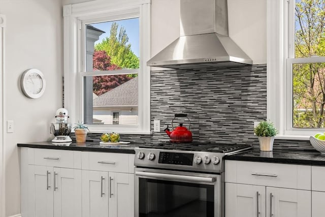 kitchen featuring stainless steel range with gas stovetop, wall chimney range hood, tasteful backsplash, and white cabinets