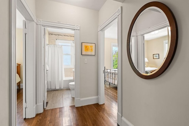 corridor with wood finished floors and baseboards