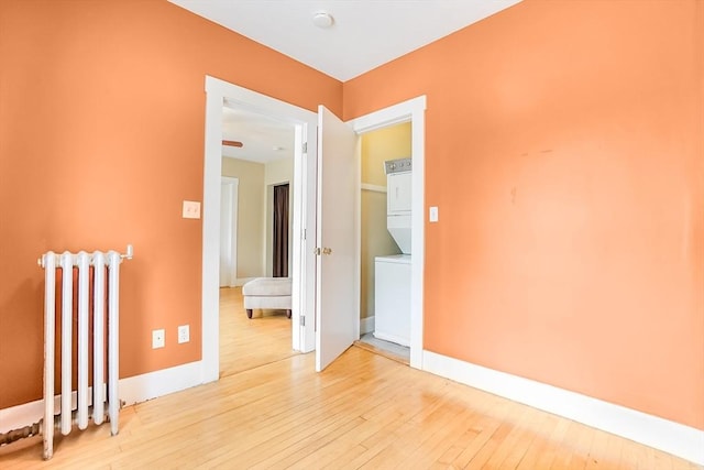 132 Myrtle St Unit 1, Waltham, MA 02453 - empty room with stacked washer / dryer, radiator, and light wood finished floors