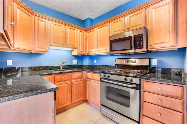 132 Myrtle St Unit 1, Waltham, MA 02453 - kitchen with stainless steel appliances, light tile patterned floors, dark stone countertops, and a textured ceiling