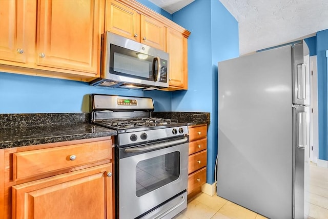 132 Myrtle St Unit 1, Waltham, MA 02453 - kitchen with appliances with stainless steel finishes, light tile patterned floors, and dark stone counters
